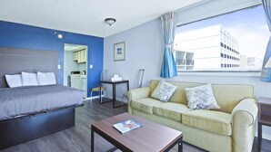 Una habitación de hotel moderna con cama, sofá, mesa de centro y vista a la ciudad.