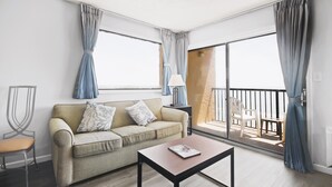 Una sala de estar moderna con un sofá, una mesa de centro y un balcón con sillas.