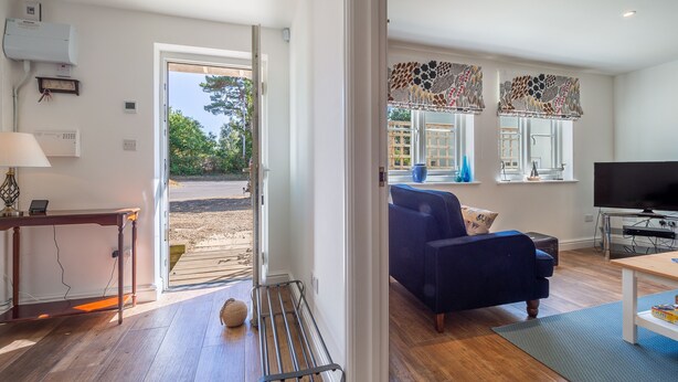 A modern living room with a blue sofa, a television, and a wooden coffee table. - Yew Tree Cottage is a modern eco-cottage (Westleton)