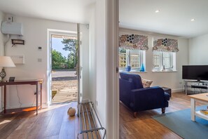 A modern living room with a blue sofa, a television, and a wooden coffee table. - Yew Tree Cottage is a modern eco-cottage (Westleton)