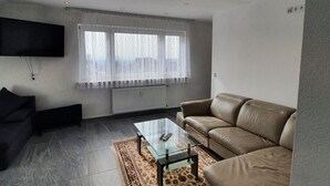 Un salon moderne avec un canapé en cuir, une table basse en verre et un téléviseur à écran plat fixé au mur.