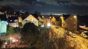 Une vue nocturne d’un quartier résidentiel, avec des maisons, des lampadaires et un pont situé au loin.