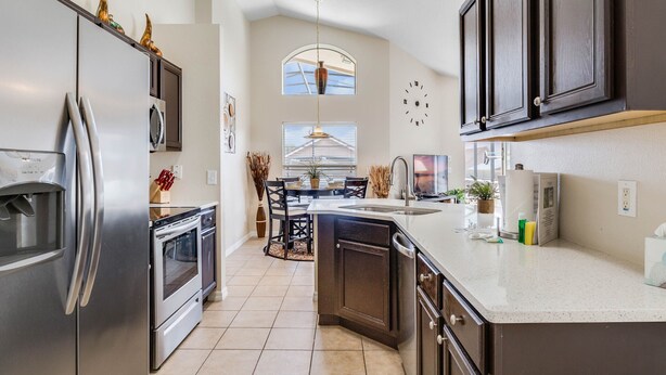 A modern kitchen with stainless steel appliances, dark cabinetry, and a large island. - SO136CA - Amazing 4 Bedrooms Pool Home with Clubhouse Access (Davenport)