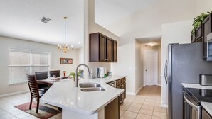 A kitchen with a central island, dark cabinets, and a refrigerator. - SO136CA - Amazing 4 Bedrooms Pool Home with Clubhouse Access (Davenport)