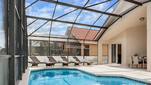 A swimming pool with lounge chairs and a glass-enclosed patio area. - SO136CA - Amazing 4 Bedrooms Pool Home with Clubhouse Access (Davenport)