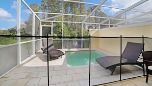 Area piscina esterna vetrata con poltroncine relax e vista sugli alberi circostanti.
