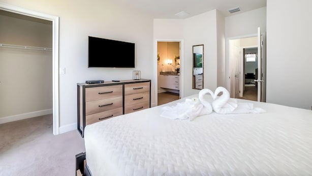 Una camera d'albergo con un letto grande, una TV a schermo piatto, una cassettiera e un armadio a tutta parete.