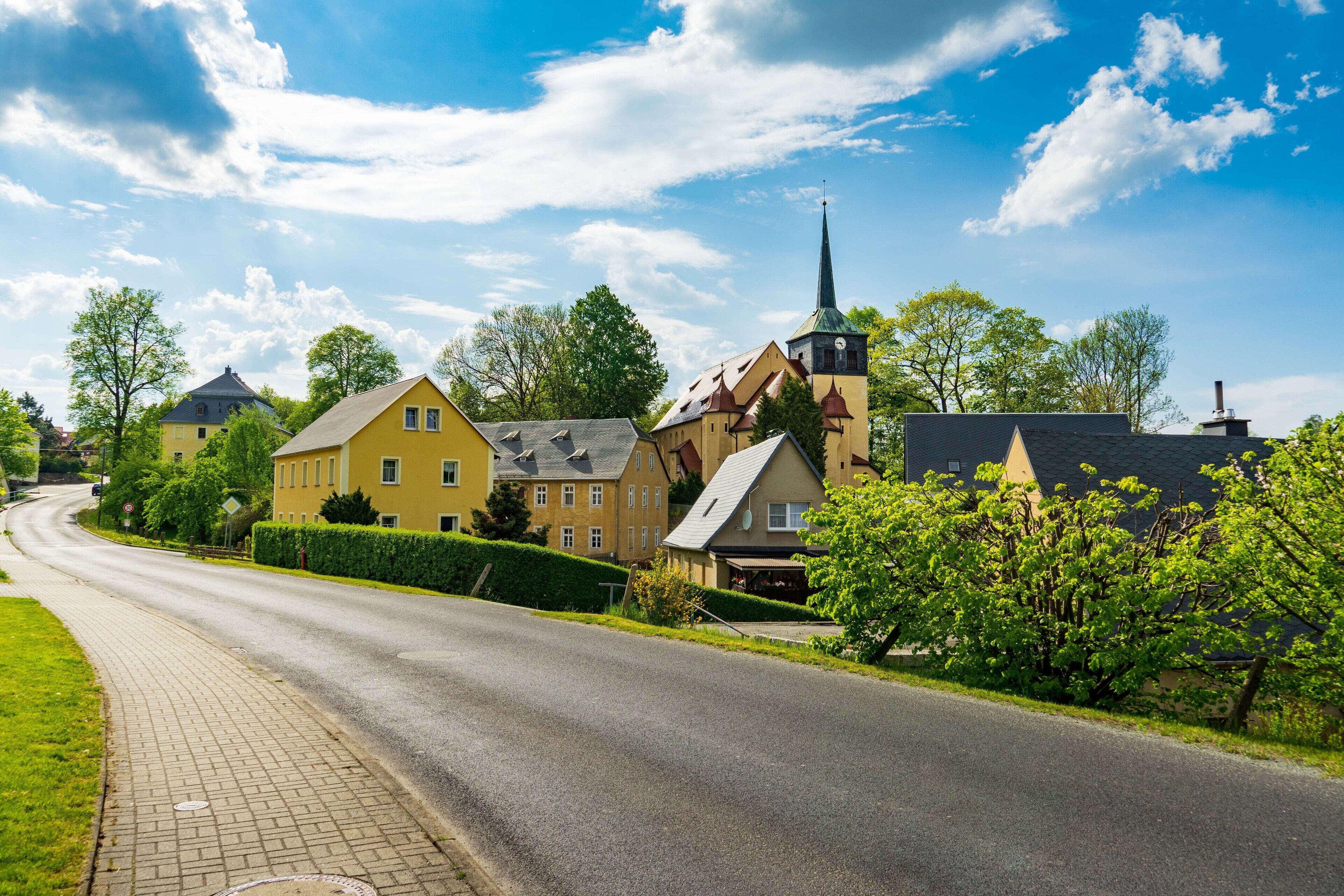 Eine Straße mit Häusern, einer Kirche und blauem Himmel.