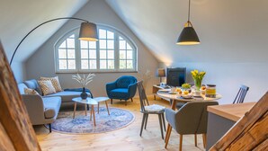Un loft moderne doté d’un haut plafond, d’un coin salon confortable avec un canapé et des fauteuils, d’une table à manger avec des chaises, et d’une grande fenêtre laissant entrer la lumière naturelle.