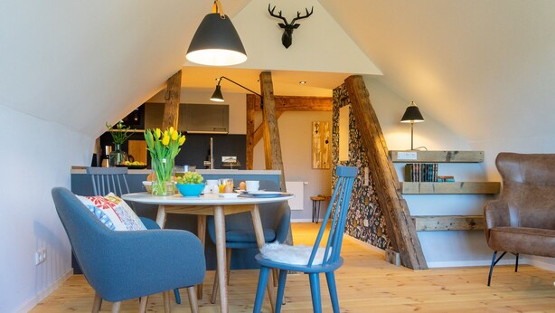 Un coin repas avec une table ronde, des chaises bleues et un lustre.