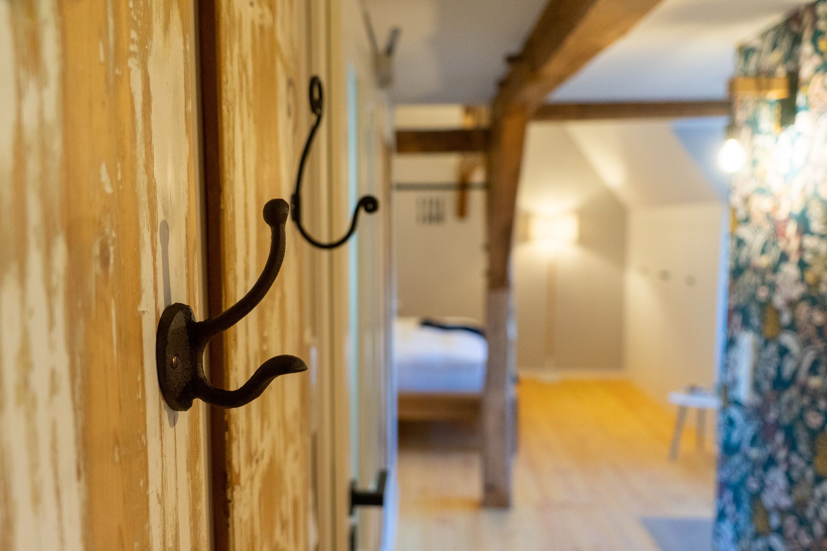 Une porte en bois avec un crochet en métal, un lit à l’arrière-plan et un mur orné de motifs.