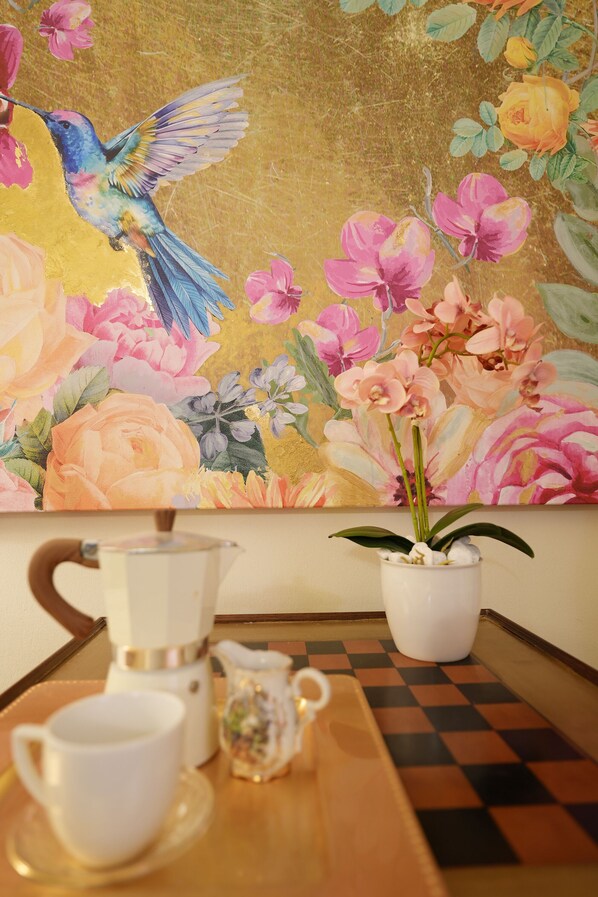 A coffee setup with a cup, a coffee pot, and a pitcher on a checkered table.