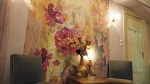 A room with two chairs, a table with a vase of flowers, and a large floral mural on the wall. - Chateau Leconte, Beautiful Vintage House in Thessaloniki (Thessaloniki)