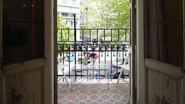 An open doorway leading to a balcony with a tiled floor, a metal railing, and a view of a building and trees. - Chateau Leconte, Beautiful Vintage House in Thessaloniki (Thessaloniki)