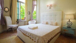 A bedroom with a large bed, a chair, a small table, and a nightstand. - Chateau Leconte, Beautiful Vintage House in Thessaloniki (Thessaloniki)