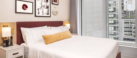 Una habitación de hotel con una cama grande, una mesita de noche con lámpara y cuadros en la pared.