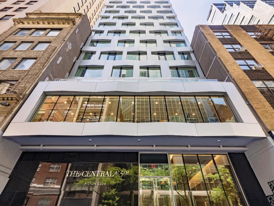 Een modern gebouw met een glazen gevel, met de tekst 'The Central 5th Hilton Club'.