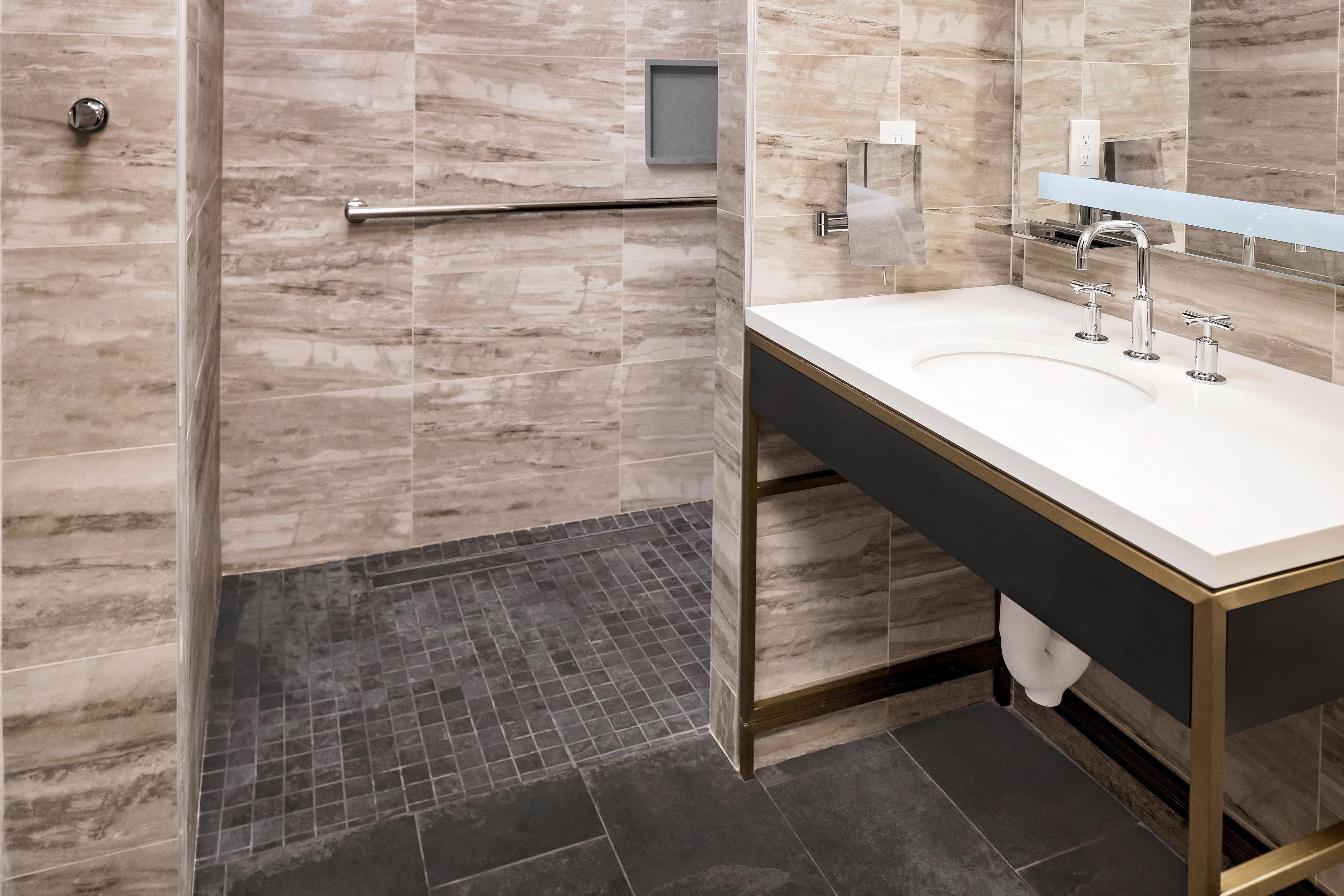 A modern bathroom with a shower, a sink, and a mirror.