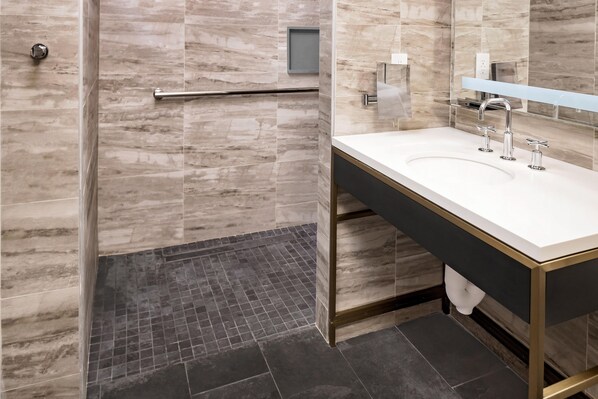 A modern bathroom with a shower, a sink, and a mirror.