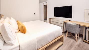 A bedroom with a bed, a desk, a chair, and a TV.