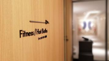 A wooden door with a sign indicating the direction to the Fitness/Hot Baths area.