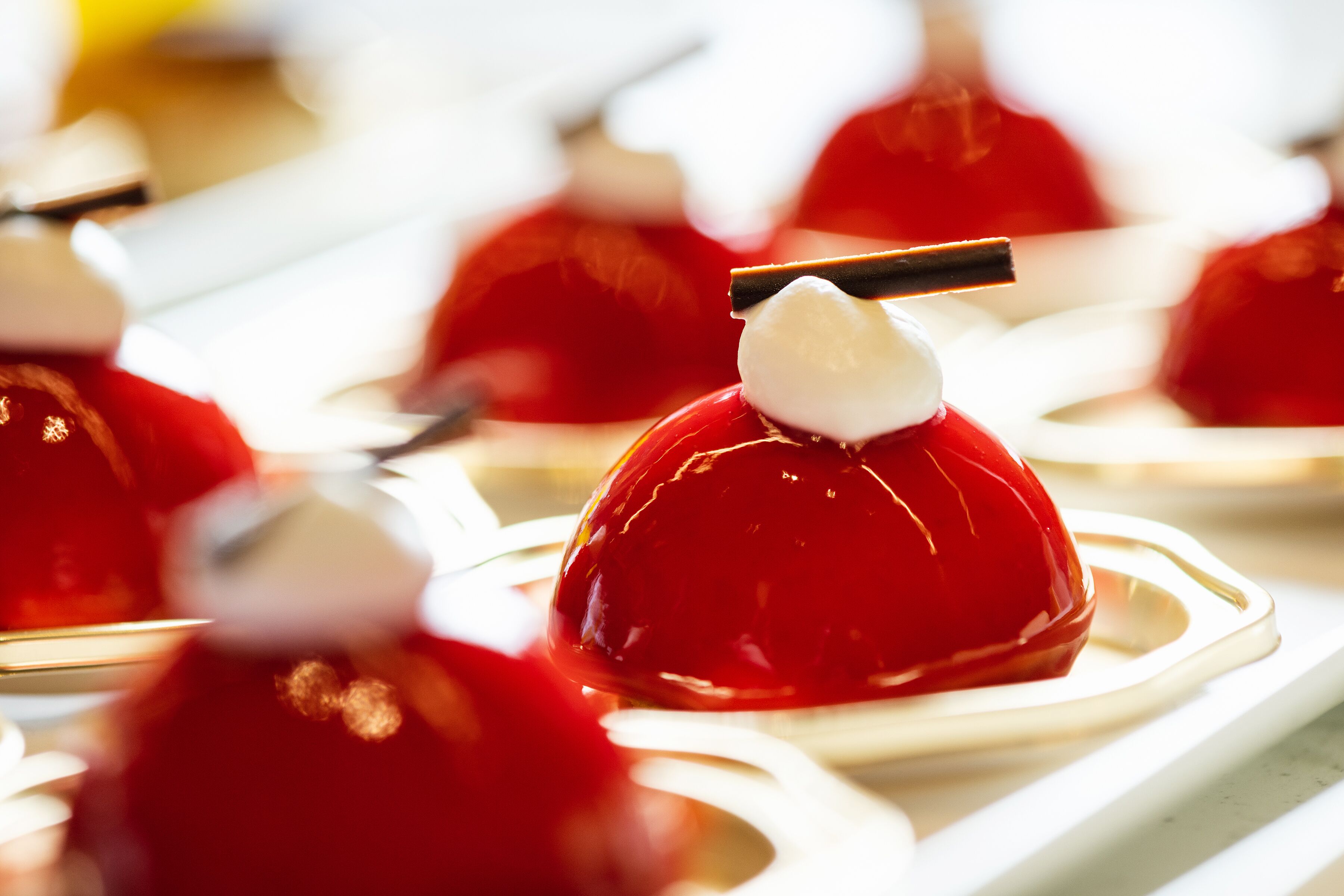 Une présentation de desserts avec des gelées rouges et une boule de crème blanche sur une assiette blanche.