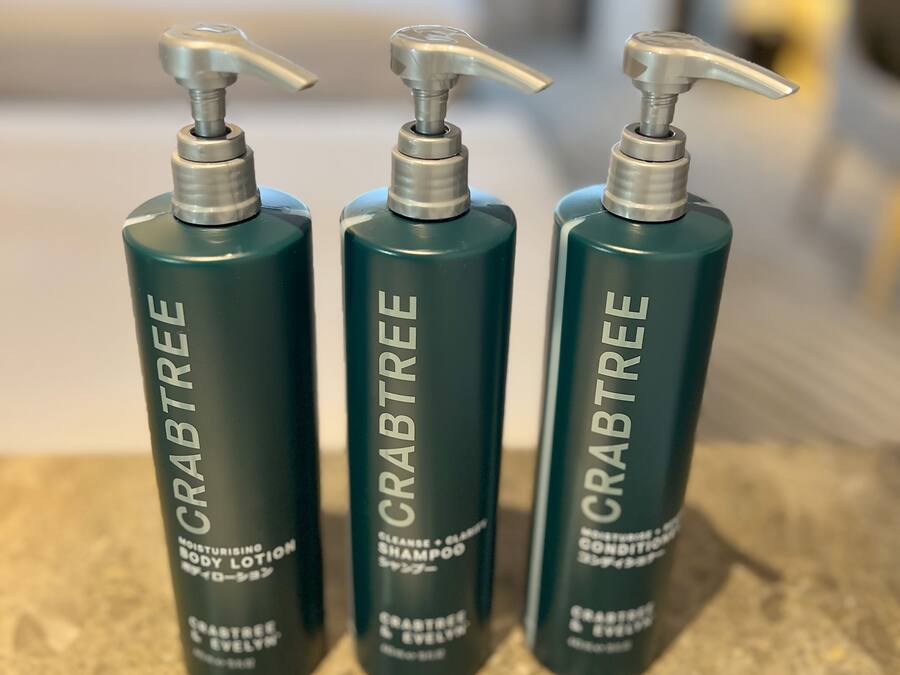 Three bottles of Crabtree body lotion, shampoo, and conditioner.