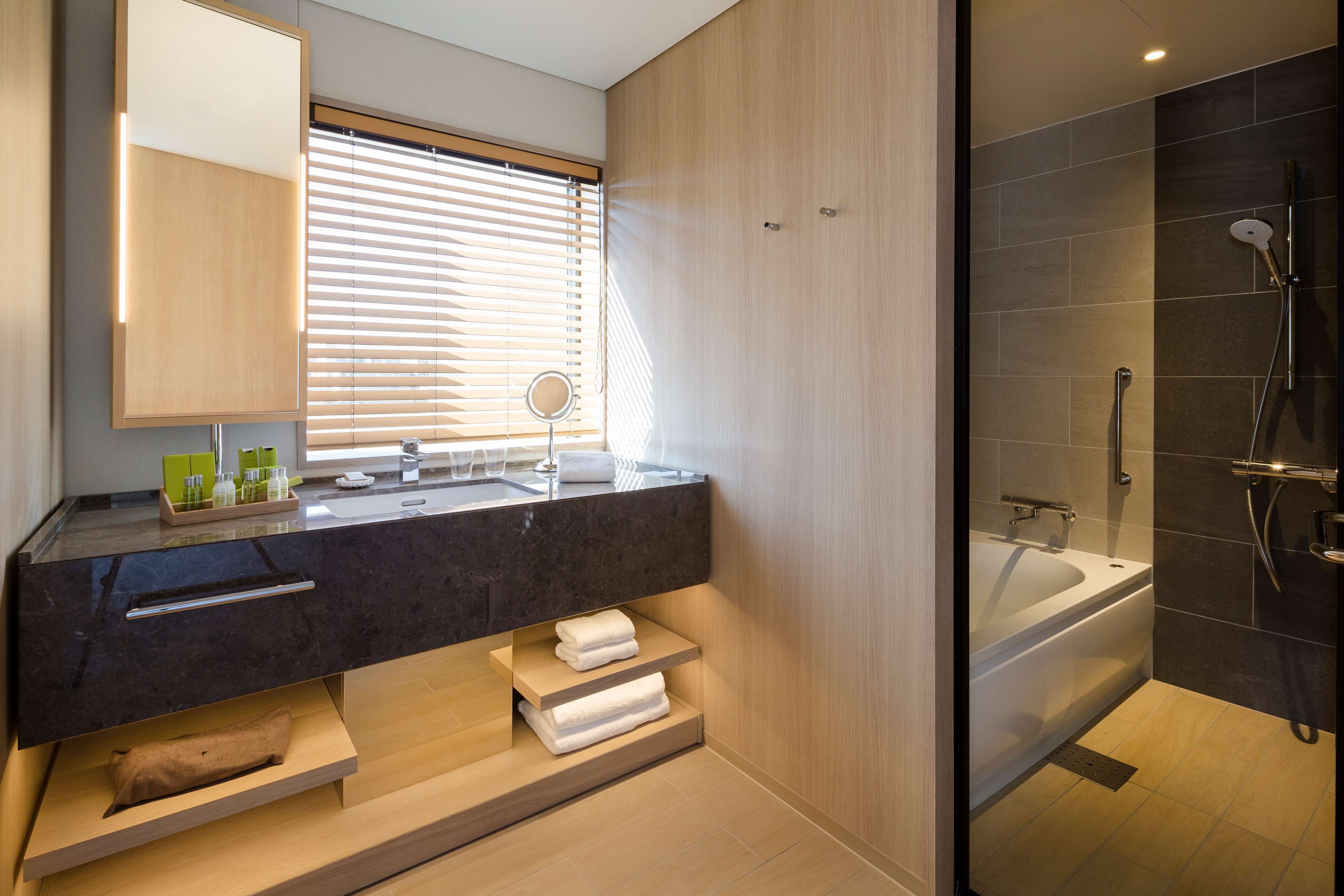 A modern bathroom with a large mirror, a vanity with a black countertop, and a separate shower area.