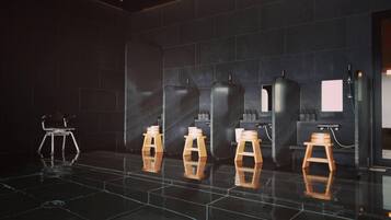 Une salle de bain moderne avec des murs recouverts de carreaux noirs, un sol noir brillant et des tabourets en bois.