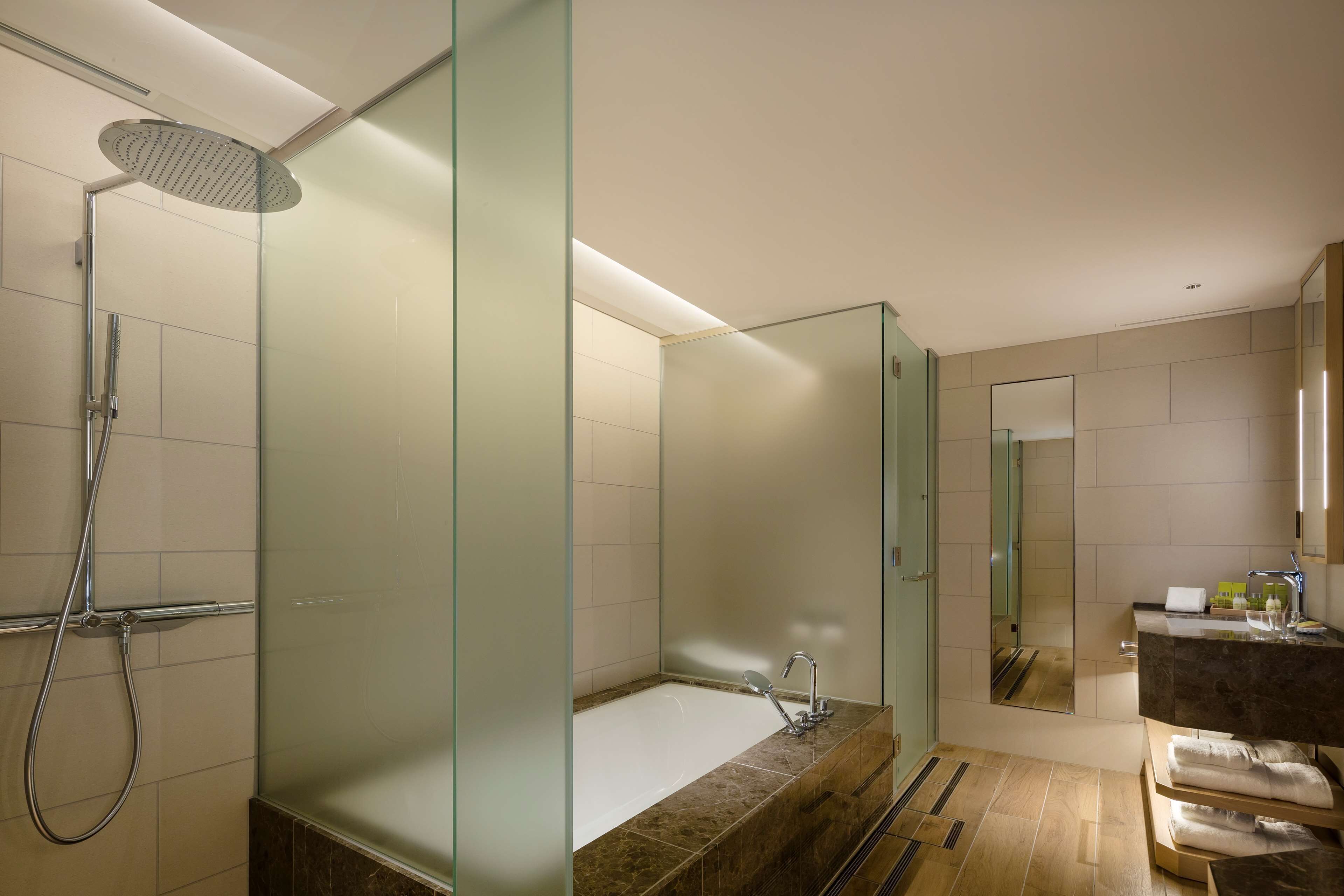A modern bathroom with a glass-enclosed shower, a freestanding bathtub, and a vanity with a mirror.