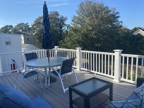 Une terrasse avec une table ronde, des chaises et une petite table d’appoint.