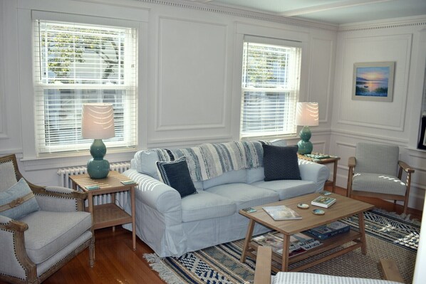 A living room with a light blue sofa, two side tables with lamps, a wooden coffee table, and a patterned rug. - Beautiful, updated 3 bedroom home with parking for 6 cars in downtown Newport (Newport)
