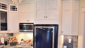A kitchen with white cabinets, a black refrigerator, a chandelier, and wooden flooring. - Beautiful,  updated 3 bedroom home with parking for 6 cars in downtown Newport (Newport)
