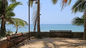 Une plage avec un banc en bois et un lampadaire, des palmiers et une vue dégagée sur la mer.