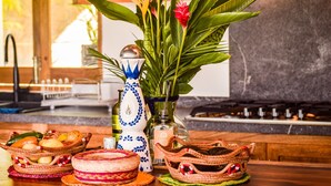 Eine Küchenarbeitsplatte mit einer dekorativen Vase, Korbwäsche und verschiedenen Früchten und Gemüsesorten.