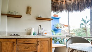 A kitchen with wooden cabinets, a white countertop, and a thatched roof.