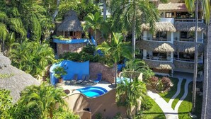 A resort with a swimming pool, thatched-roof structures, and lush greenery.