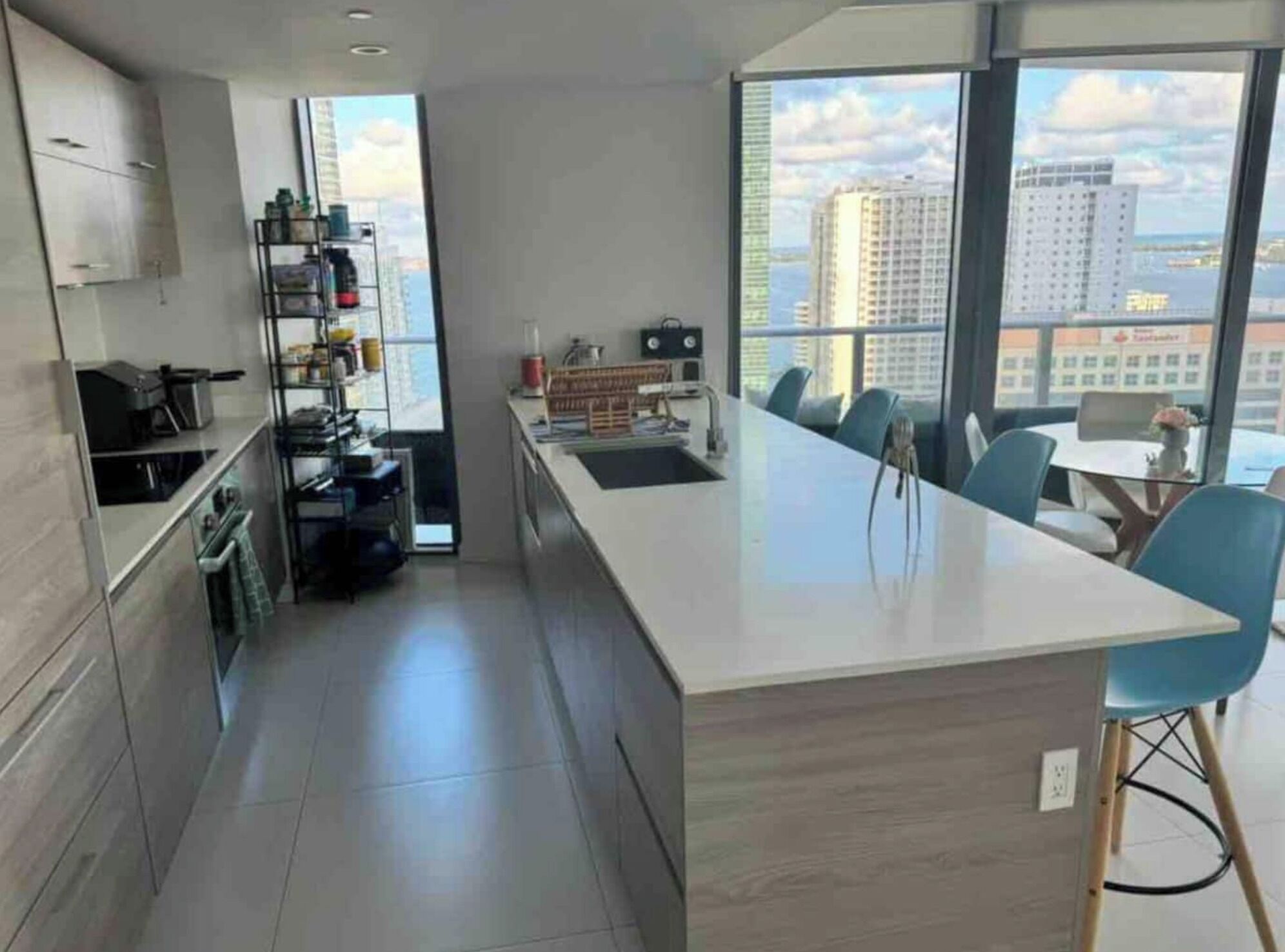 A modern kitchen with a central island, built-in cabinets, and a view of the city through large windows.