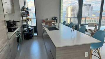 A modern kitchen with a central island, built-in cabinets, and a view of the city through large windows.