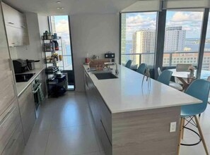 A modern kitchen with a central island, built-in cabinets, and a view of the city through large windows.