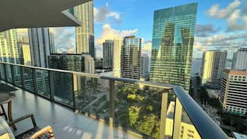 A high-rise building with a glass facade, a balcony with a metal railing, and a view of other buildings.