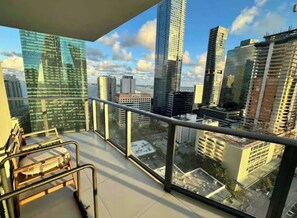A balcony with a city view, metal railings, and a chair.