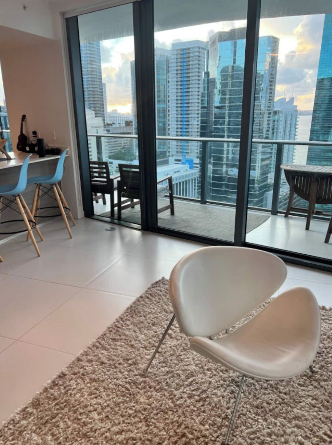 A modern living room with a large glass door leading to a balcony with a city view.