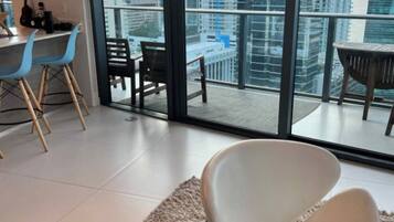 A modern living room with a large glass door leading to a balcony with a city view.