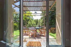 A glass door leading to an outdoor patio with a table and chairs, a hanging light fixture, and a wooden deck.