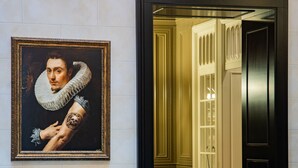 Una habitación con un sofá tapizado azul, un retrato enmarcado en la pared y un espejo con marco negro.