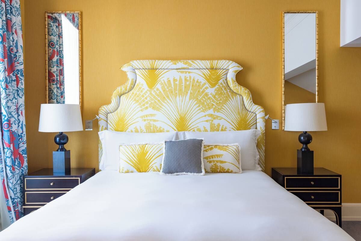 A hotel room with a large bed, two bedside tables, and a mirror on the wall.