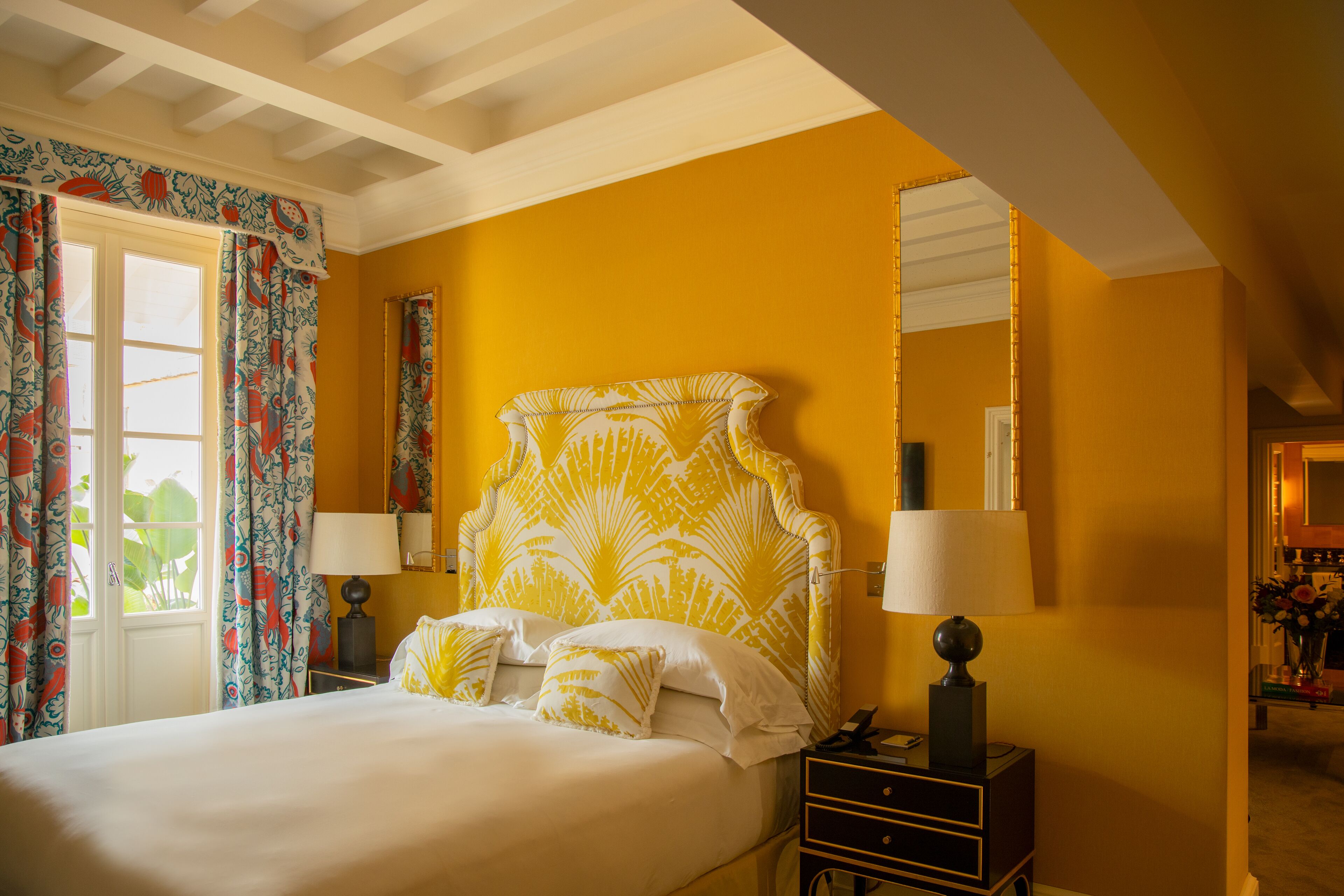A bedroom with a bed, nightstands, lamps, and a mirror.