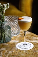 Un bicchiere da cocktail con una schiuma densa, appoggiato su un tavolo di marmo.