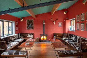 Una habitación acogedora con paredes rojas, una chimenea central y asientos tapizados en cuero de vaca.